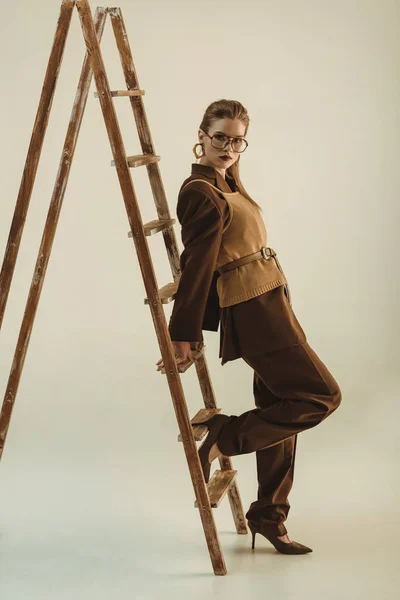 Menina bonita em estilo vintage posando perto de escada de madeira no bege — Fotografia de Stock