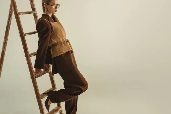 Beautiful model in retro style posing near wooden ladder isolated on beige — Stock Photo