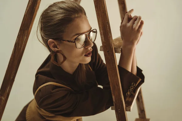 Attraente donna elegante posa vicino scala di legno isolato su beige — Foto stock