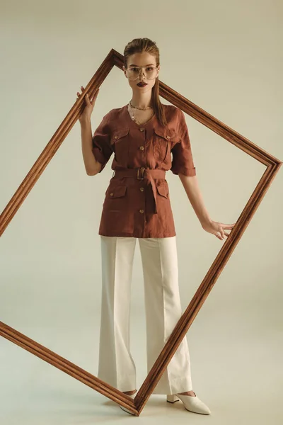 Stylish girl in retro style posing with big wooden frame — Stock Photo