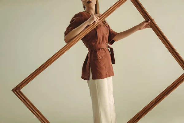 Abgeschnittene Ansicht einer Frau im Vintage-Stil posiert mit großem Holzrahmen isoliert auf Beige — Stockfoto