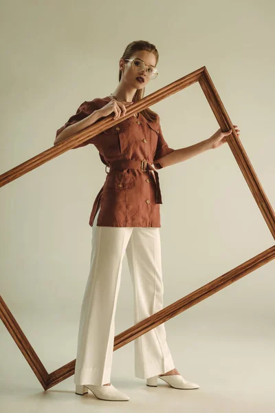 Красивая модная девушка в винтажном стиле позирует с большой деревянной рамой — стоковое фото