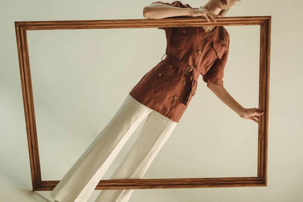 Vista ritagliata della donna alla moda in stile vintage in posa con grande telaio in legno — Foto stock