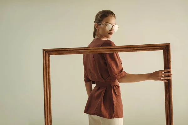 Model in vintage style posing with big wooden frame isolated on beige — Stock Photo