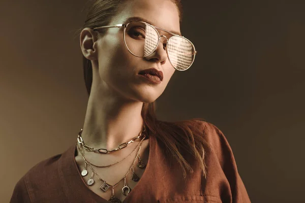 Hermosa mujer elegante posando en gafas de moda aislado en marrón - foto de stock