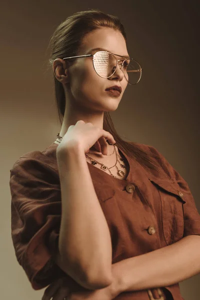 Atractiva mujer elegante posando en gafas aisladas en marrón - foto de stock