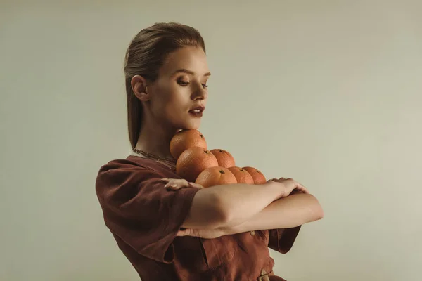 Hermosa mujer de moda sosteniendo naranjas frescas aisladas en beige - foto de stock