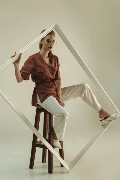 Bela jovem mulher posando no banquinho com grande quadro branco — Fotografia de Stock