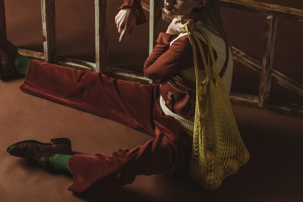 Cropped view of girl with lemons in string bag posing near ladder — Stock Photo