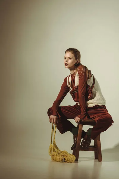 Mulher elegante atraente sentado no banquinho com limões em saco de corda no bege — Fotografia de Stock