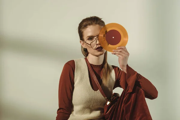 Atraente jovem mulher segurando vintage vinil registro no bege — Fotografia de Stock