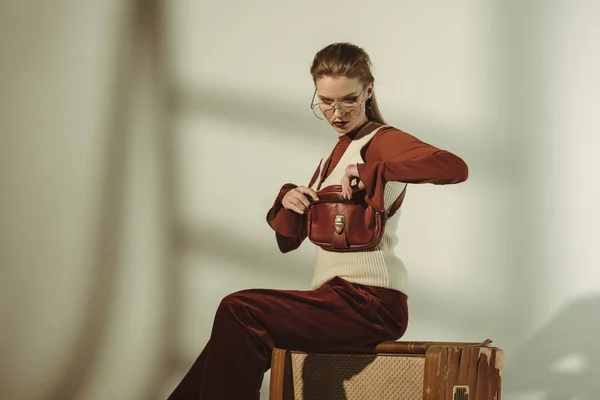 Atractiva mujer joven con estilo y sentado en la televisión vintage en beige - foto de stock