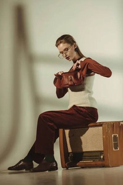 Bela menina da moda e sentado na tv vintage no bege — Fotografia de Stock