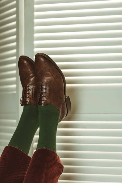 Vista parcial de las piernas femeninas en zapatos de cuero retro cerca de la pantalla plegable - foto de stock