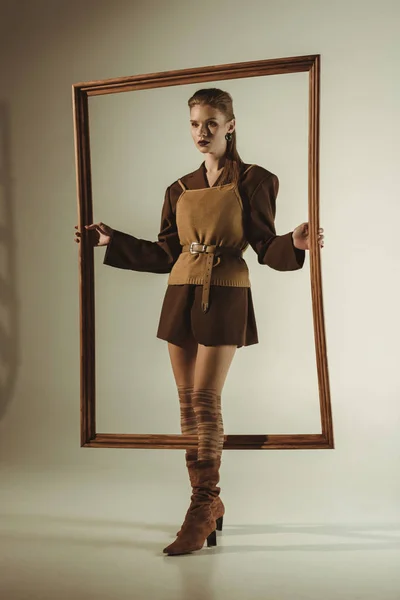 Attractive woman in vintage style posing with big wooden frame — Stock Photo