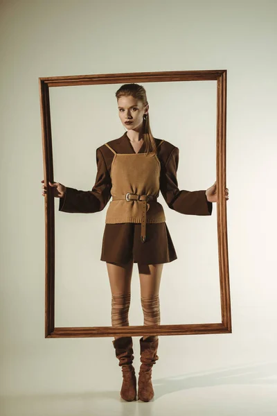 Beautiful fashionable woman in vintage style posing with big wooden frame — Stock Photo