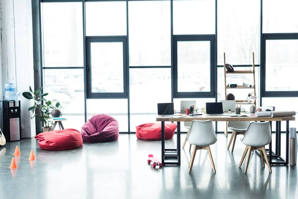 Modernes Design des geräumigen Loft-Büros mit Sitzsäcken und Tisch mit Laptops — Stockfoto