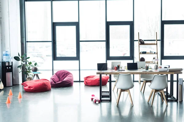 Design moderne de bureau loft spacieux avec des chaises de sac de haricot et table avec des ordinateurs portables — Photo de stock