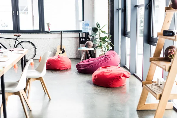 Design moderne de bureau loft spacieux avec des chaises de sac de haricot, rack en bois et table — Photo de stock