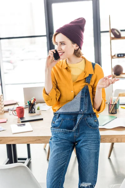 Designer feminino gesticulando com a mão e usando smartphone no escritório loft — Fotografia de Stock