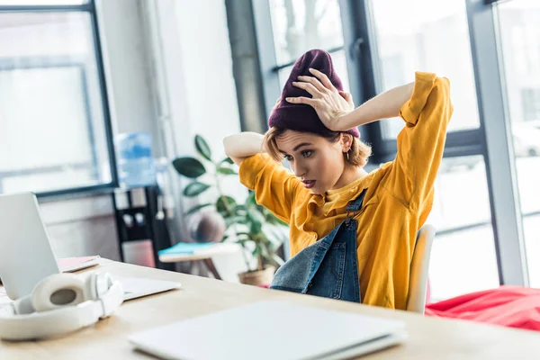 Confused young female it specialist using laptop in loft office — Stock Photo