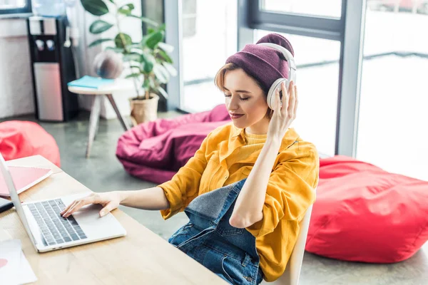 Joven hembra es especialista en auriculares usando portátil en la oficina loft - foto de stock