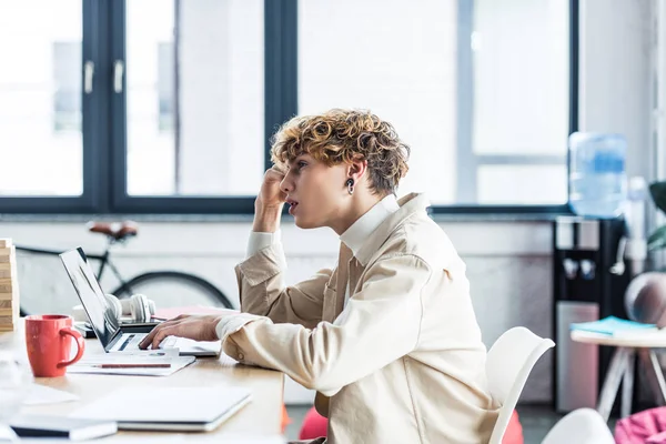 Bello è specialista seduto alla scrivania e utilizzando il computer portatile in ufficio loft — Foto stock