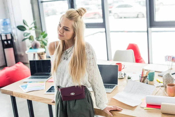 Belle architecte près de la table avec des plans et des ordinateurs portables dans le bureau loft — Photo de stock