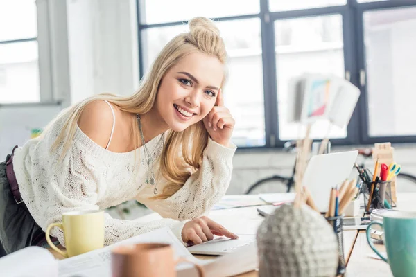 Schöne, lässige Geschäftsfrau, die am Schreibtisch arbeitet und im Loft-Büro in die Kamera schaut — Stockfoto