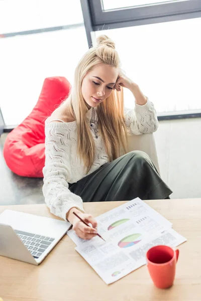 Femme d'affaires occasionnelle assise à table et travaillant sur des graphiques dans le bureau loft — Photo de stock