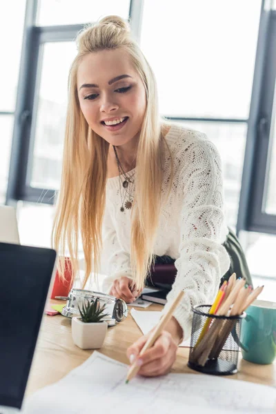 Beautiful smiling female architect working on blueprint in loft office — Stock Photo