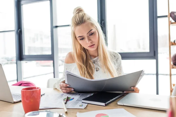 Belle femme d'affaires occasionnelle assise au bureau et tenant le document dans le bureau loft — Photo de stock