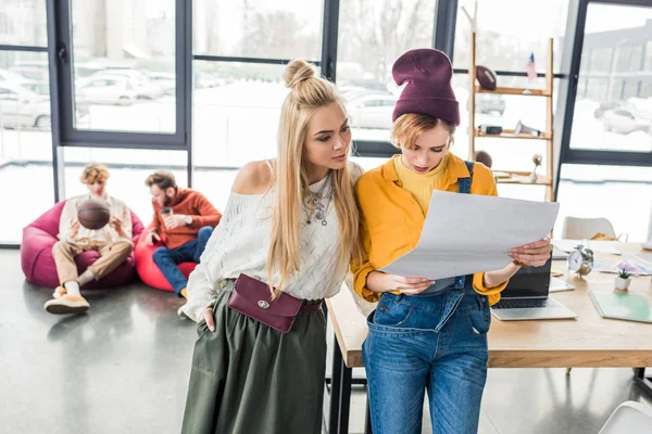 Beautiful focused female architects working on blueprint in loft office — Stock Photo