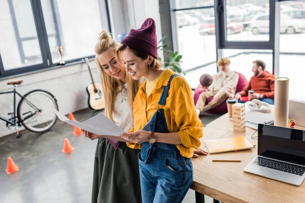Beautiful smiling female architects working on blueprint in loft office — Stock Photo