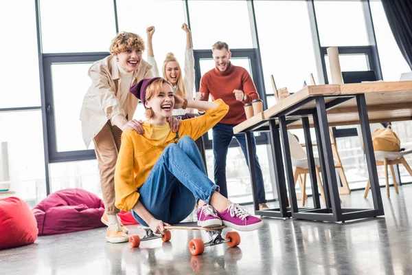 Happy casual business colleagues having fun and riding skateboard in loft office — Stock Photo