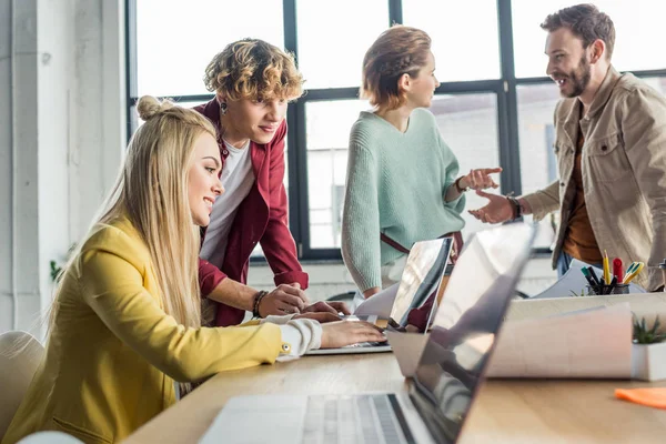 Grupo de arquitectos femeninos y masculinos que trabajan en la computadora portátil y tienen discusión en la oficina loft - foto de stock