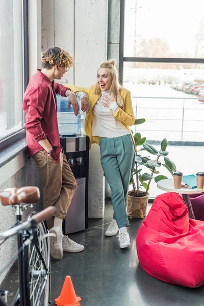 Hombre de negocios casual y mujer emocionada hablando en la oficina loft - foto de stock