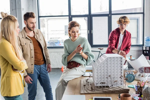 Groupe concentré d'architectes féminins et masculins travaillant ensemble sur modèle de maison dans le bureau loft — Photo de stock