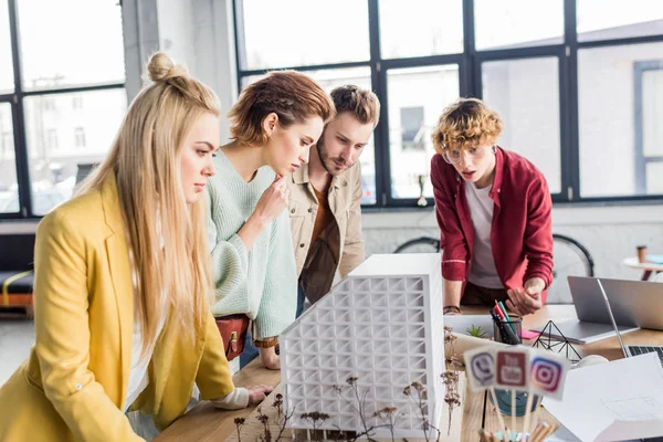 Concentrated group of female and male architects working together on house model in loft office — Stock Photo