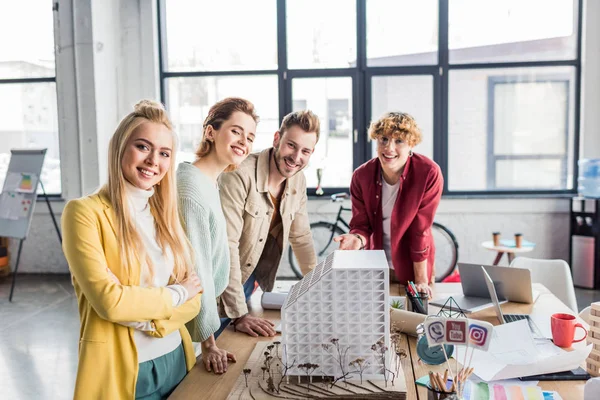 Sorrindo grupo de arquitetos do sexo feminino e masculino trabalhando juntos no modelo de casa no escritório loft — Fotografia de Stock