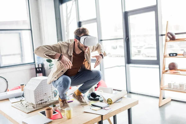 Männlicher Designer gestikuliert mit den Händen, während er Virtual-Reality-Erfahrung im Loft-Büro mit Kopierraum hat — Stockfoto