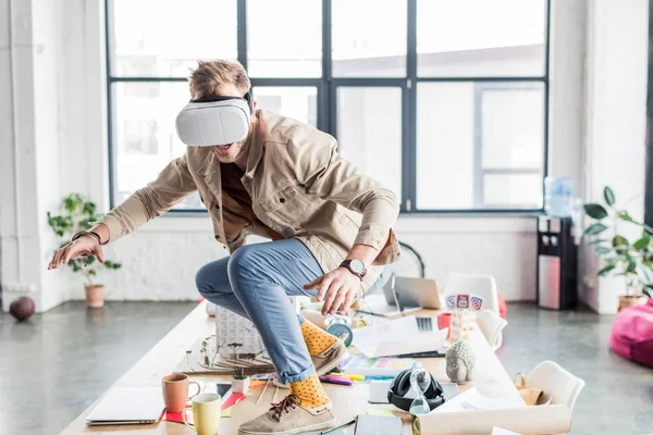 Diseñador masculino gesto con las manos mientras tiene experiencia de realidad virtual en la oficina loft - foto de stock