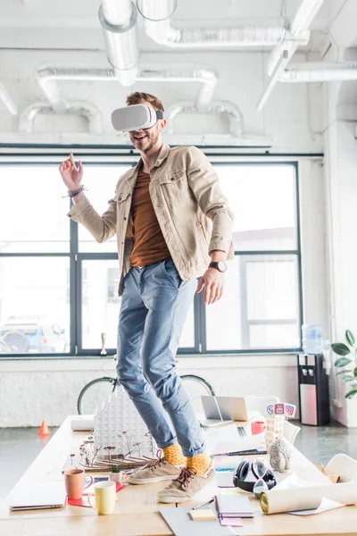 Arquitecto masculino gesticulando con las manos mientras tiene experiencia de realidad virtual en la oficina loft - foto de stock