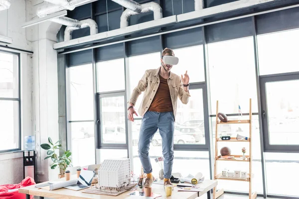 Architecte masculin gestuelle avec les mains tout en ayant une expérience de réalité virtuelle dans le bureau loft avec espace de copie — Photo de stock