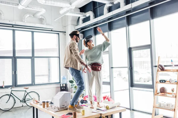 Female and male designers gesturing with hands and having virtual reality experience in loft office with copy space — Stock Photo