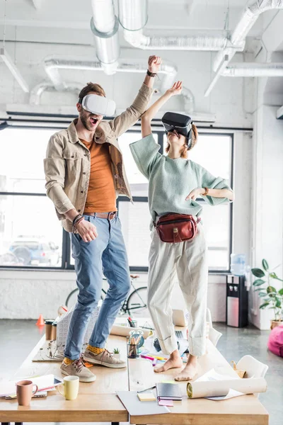 Female and male designers wearing vr headset, gesturing with hands and having virtual reality experience in loft office — Stock Photo