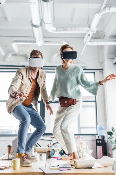 Designers féminins et masculins gesticulant avec les mains tout en ayant une expérience de réalité virtuelle dans le bureau loft — Photo de stock