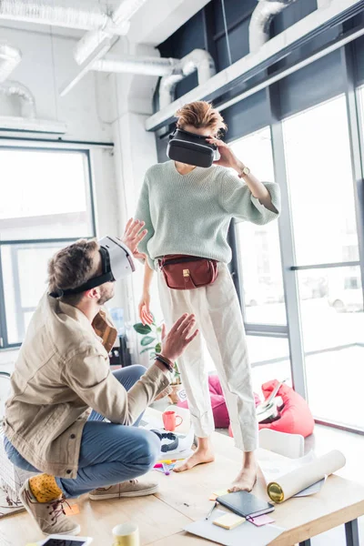Designers féminins et masculins gesticulant avec les mains tout en ayant une expérience de réalité virtuelle dans le bureau loft — Photo de stock