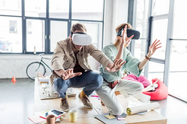 Збуджена жінка і чоловік архітектори жестикулюють руками, маючи досвід віртуальної реальності в офісі лофт — стокове фото