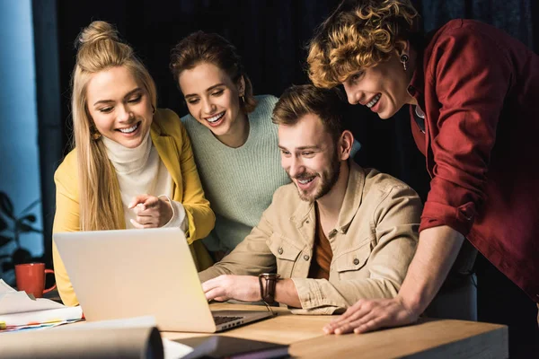 Grupo sonriente de especialistas que utilizan el ordenador portátil en la oficina - foto de stock